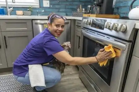 Home Cleaning Technician cleaning the outside of the oven in a client's home.